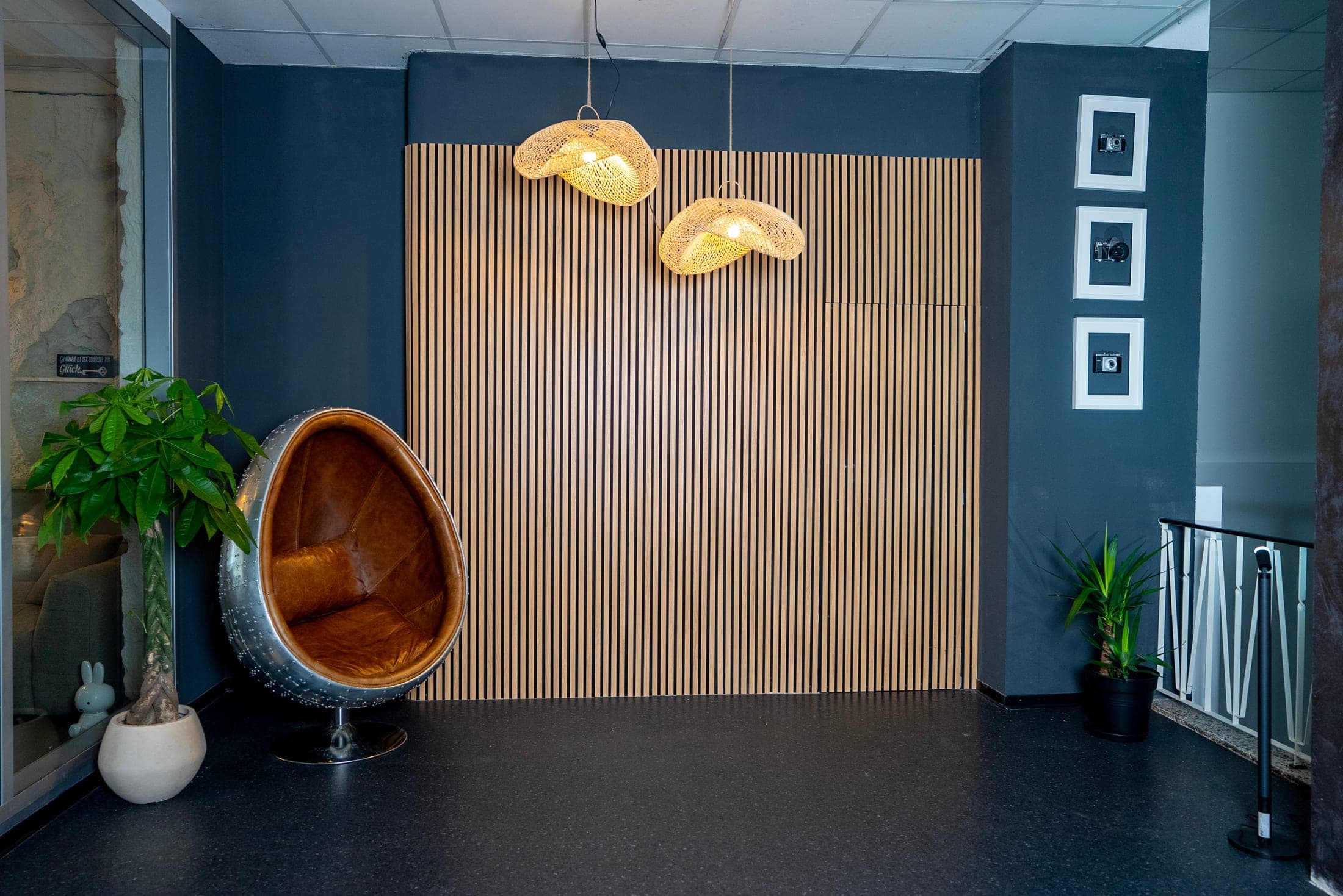 Lounge-Kulisse mit Holz-Latten-Wand und braunem Egg-Chair