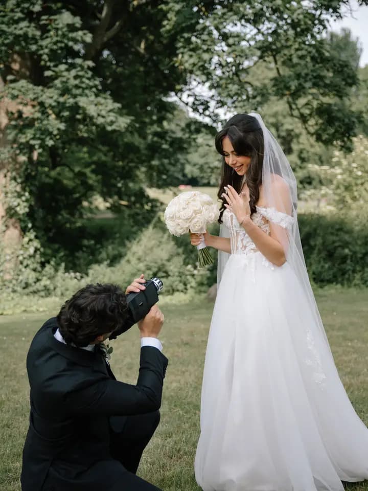 Der Fotograf kniet im Park und fotografiert die Braut