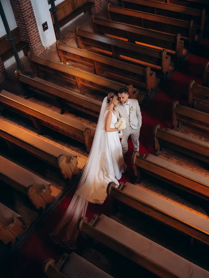 Brautpaar zwischen den Kirchenbänken, von oben fotografiert